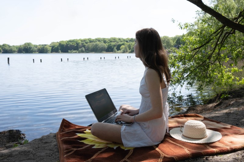 Frau lernt mit Laptop am See