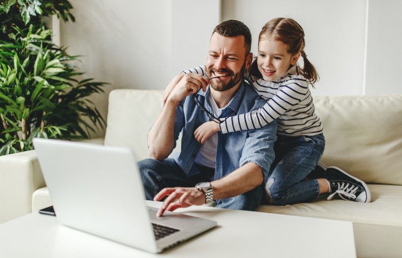Vater und Tochter auf Sofa vor Laptop